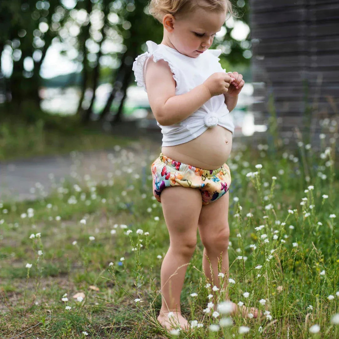Enfant debout dans l'herbe portant une culotte d'apprentissage cousue à la main en Europe, motif papillons – Presque Grand
