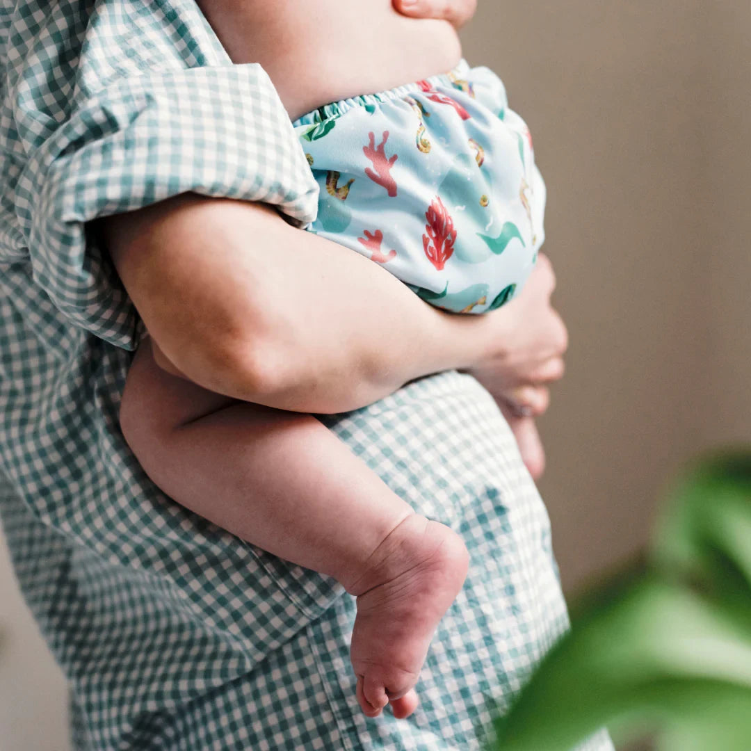Parent portant son bébé en culotte d'apprentissage bleue, adaptée à la crèche et aux sorties – Presque Grand
